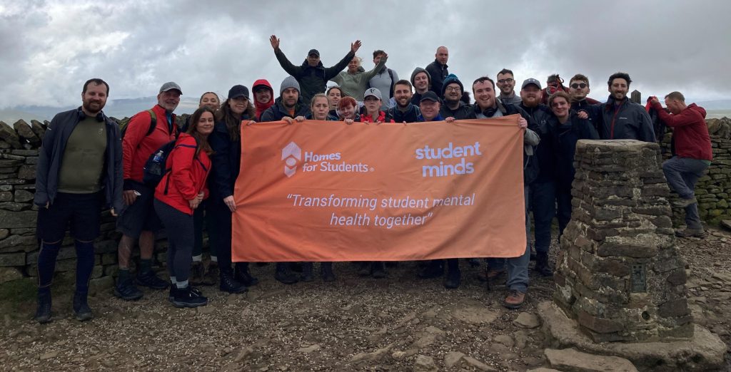 Homes for Students colleagues on top of the mountain with a Student Minds flag